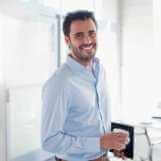 Portrait of smiling businessman holding coffee cup in office